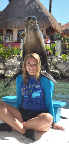A future dolphin trainer at ABC Animal Training smiles while a sea lion perches on her shoulders
